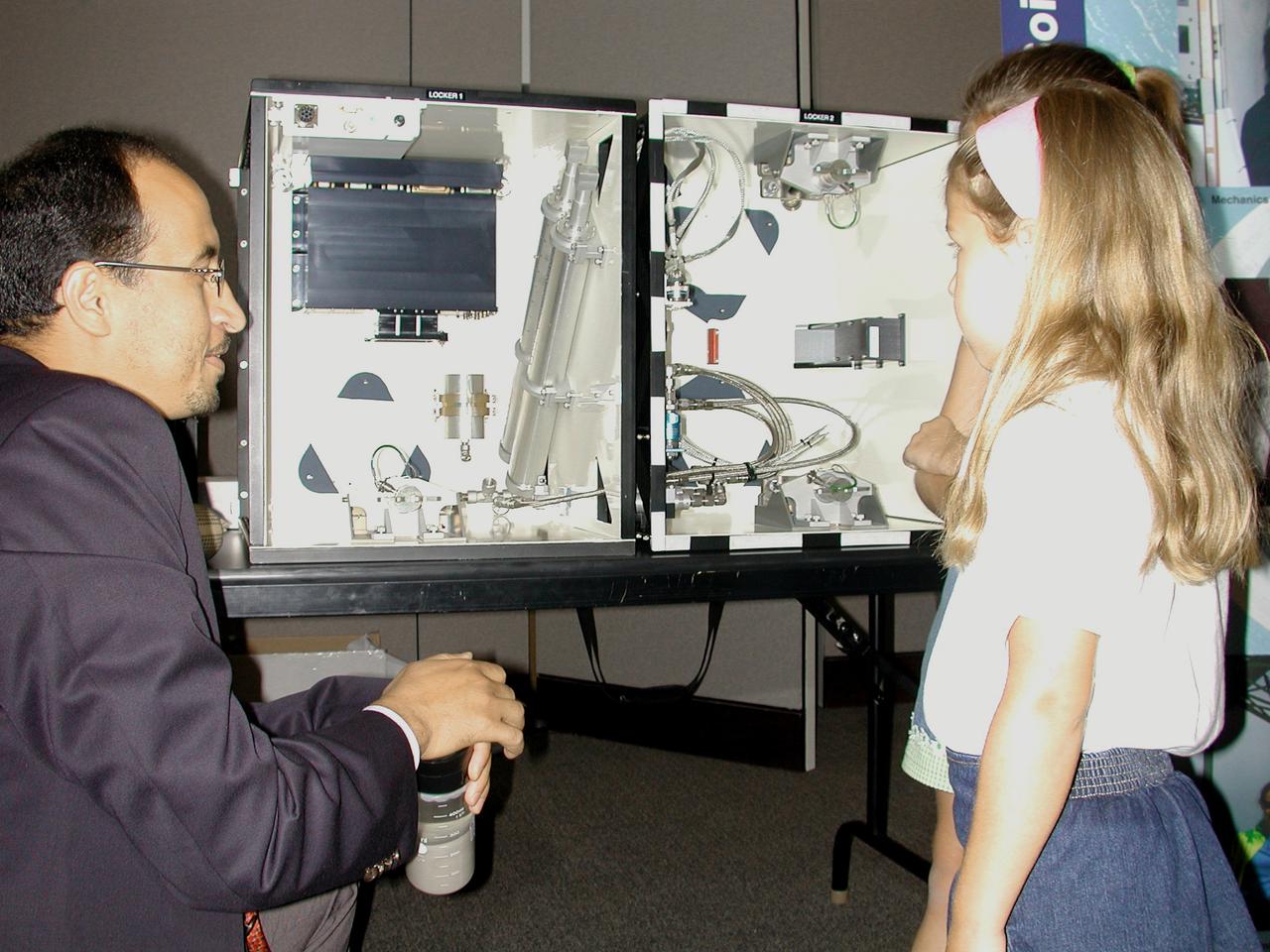 Khalid Alshibli of Louisiana State University, project scientist for the Mechanics of Granular Materials (MGM-III) experiment, uses a jar of sand and a training model of the MGM apparatus to explain the experiment to two young Virginia students. The activity was part of the Space Research and You education event held by NASA's Office of Biological and Physical Research on June 25, 2002, in Arlington, VA, to highlight the research that will be conducted on STS-107.