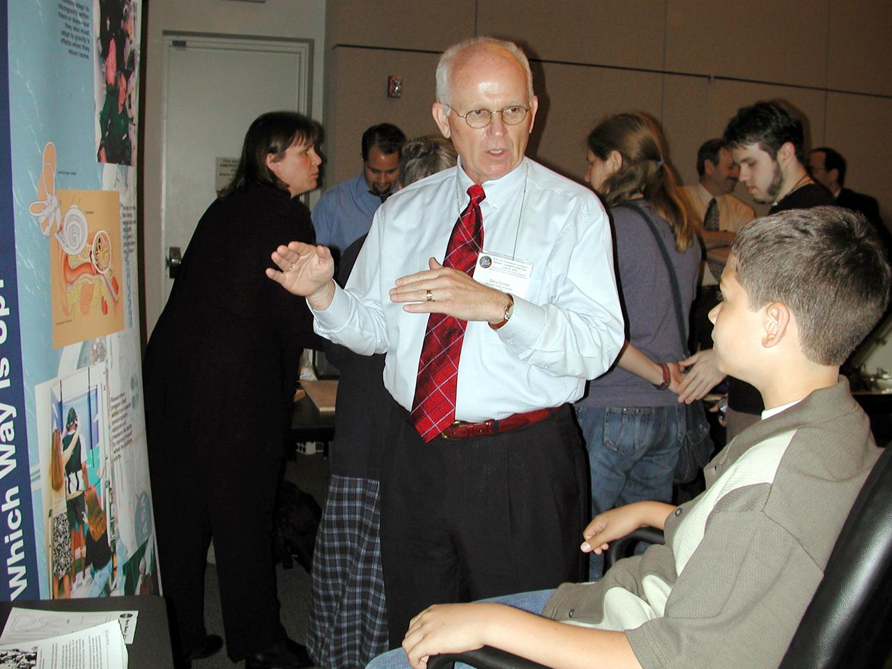 Gary Coulter, a special assistant to NASA's life sciences researchers, explains the workings of the irner ear to a Virginia student. The chair rotates to disorient the vestibular system in a simulation of research on how astronauts adapt to space and readapt to Earth. The activity was part of the Space Research and You education event held by NASA's Office of Biological and Physical Research on June 25, 2002, in Arlington, VA, to highlight the research that will be conducted on STS-107.