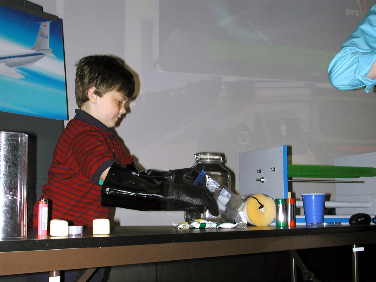 A Virginia student wears gloves to simulate the awkward feel and dexterity that astronauts experience when working in spacesuits. The activity was part of the Space Research and You education event held by NASA's Office of Biological and Physical Research on June 25, 2002, in Arlington, VA, to highlight the research that will be conducted on STS-107. (Digital camera image; no film original.
