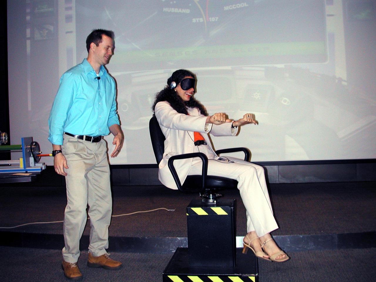 Brad McLain for the Space Biology Museum Network spins a volunteer in a rotating chair to illustrate how dependent the human vestibular system is on visual cues. The volunteer's thumbs indicate which way she thinks she is turning. Similar tests are conducted on astronauts to study how they adapt to space and readapt to Earth. The activity was part of the Space Research and You education event held by NASA's Office of Biological and Physical Research on June 25, 2002, in Arlington, VA, to highlight the research that will be conducted on STS-107.