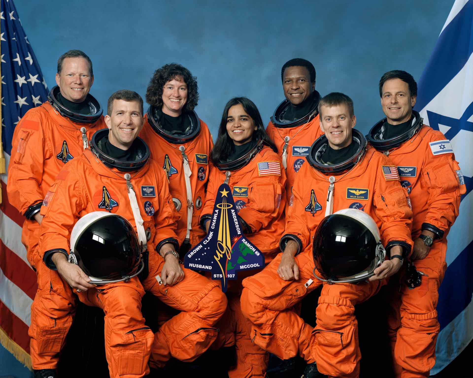 Portrait of the STS-107 crew in their orange spacesuits with the US flag and the Israeli flag in the background
