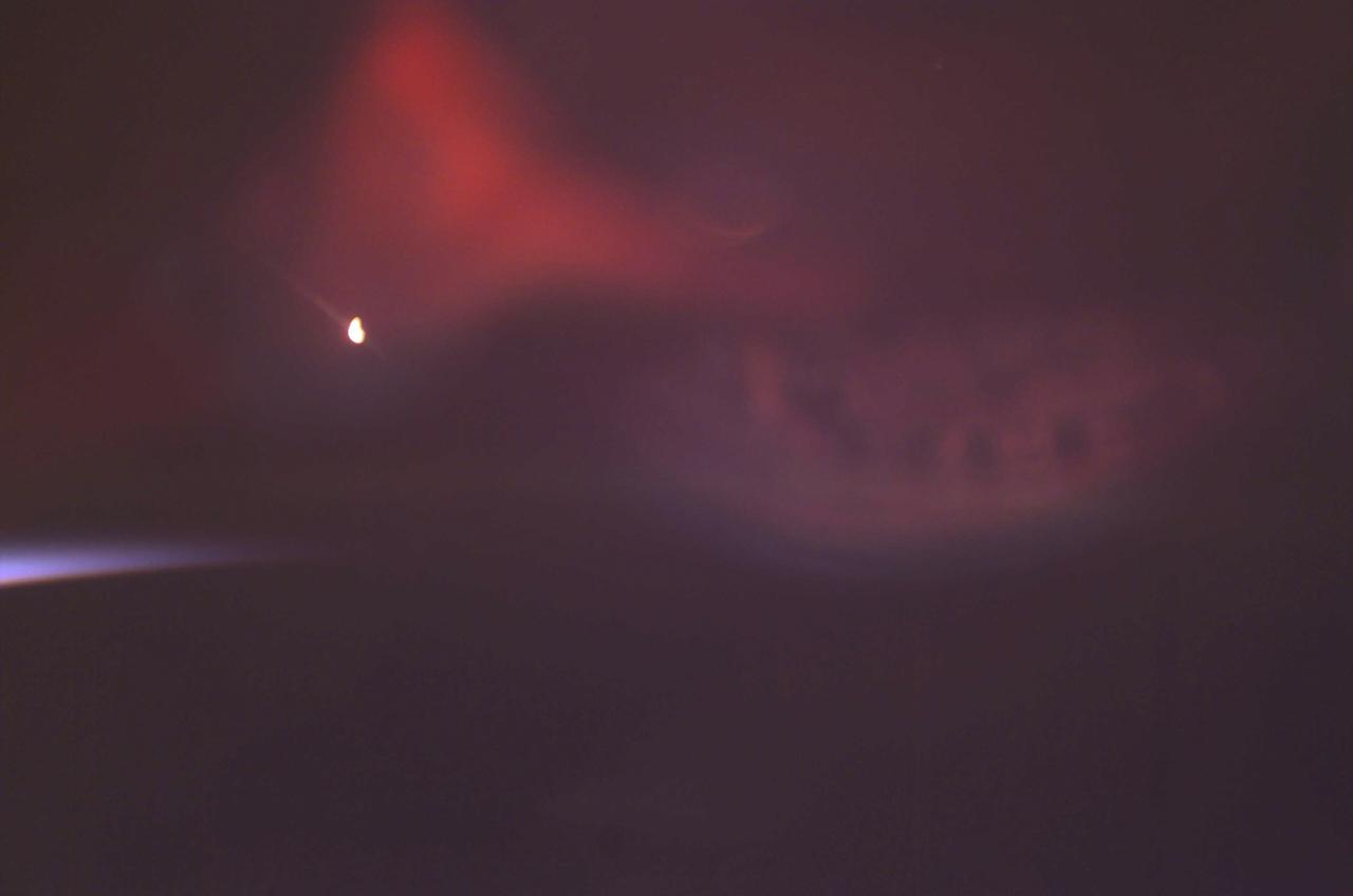 Auroras are caused when high-energy electrons pour down from the Earth's magnetosphere and collide with atoms. Red aurora, as captured here by a still digital camera aboard the International Space Station (ISS), occurs from 200 km to as high as 500 km altitude and is caused by the emission of 6300 Angstrom wavelength light from oxygen atoms. The light is emitted when the atoms return to their original unexcited state. The white spot in the image is from a light on inside of the ISS that is reflected off the inside of the window. The pale blue arch on the left side of the frame is sunlight reflecting off the atmospheric limb of the Earth. At times of peaks in solar activity, there are more geomagnetic storms and this increases the auroral activity viewed on Earth and by astronauts from orbit.