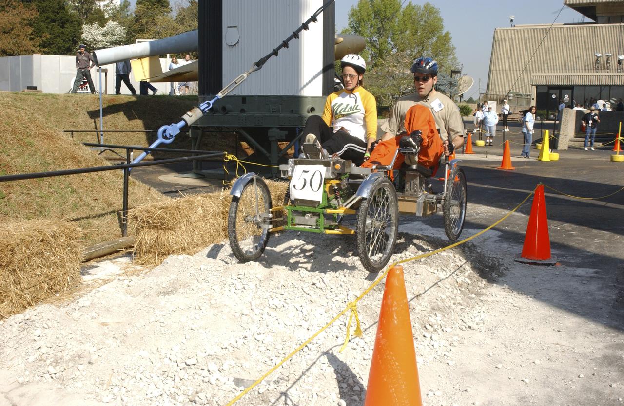 Students from across the United States and as far away as Puerto Rico came to Huntsville, Alabama for the 10th annual Great Moonbuggy Race at the U.S. Space Rocket Center. Sixty-eight teams, representing high schools and colleges from all over the United States, and Puerto Rico, raced human powered vehicles over a lunar-like terrain. Vehicles powered by two team members, one male and one female, raced one at a time over a half-mile obstacle course of simulated moonscape terrain. The competition is inspired by development, some 30 years ago, of the Lunar Roving Vehicle (LRV), a program managed by the Marshall Space Flight Center. The LRV team had to design a compact, lightweight, all-terrain vehicle that could be transported to the Moon in the small Apollo spacecraft. The Great Moonbuggy Race challenges students to design and build a human powered vehicle so they will learn how to deal with real-world engineering problems similar to those faced by the actual NASA LRV team. In this photograph, Team No. 1 from North Dakota State University in Fargo conquers one of several obstacles on their way to victory. The team captured first place honors in the college level competition.