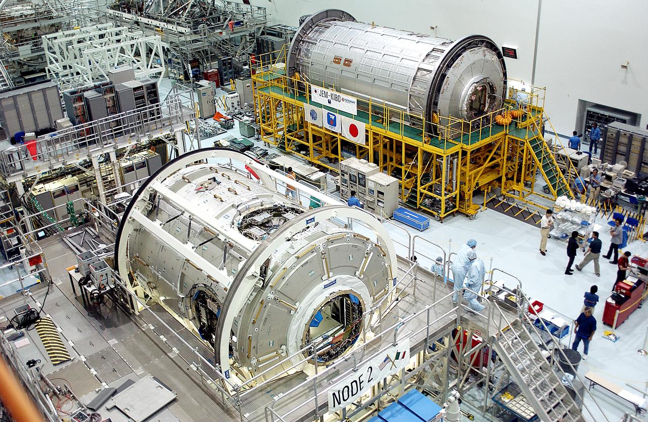 Lining the walls of the Space Station Processing Facility at the Kennedy Space Center (KSC) are the launch awaiting U.S. Node 2 (lower left). and the first pressurized module of the Japanese Experimental Module (JEM) (upper right), named "Kibo" (Hope). Node 2, the "utility hub" and second of three connectors between International Space Station (ISS) modules, was built in the Torino, Italy facility of Alenia Spazio, an International contractor based in Rome. Japan's major contribution to the station, the JEM, was built by the Space Development Agency of Japan (NASDA) at the Tsukuba Space Center near Tokyo and will expand research capabilities aboard the station. Both were part of an agreement between NASA and the European Space Agency (ESA). The Node 2 will be the next pressurized module installed on the Station. Once the Japanese and European laboratories are attached to it, the resulting roomier Station will expand from the equivalent space of a 3-bedroom house to a 5-bedroom house. The Marshall Space Center in Huntsville, Alabama manages the Node program for NASA.