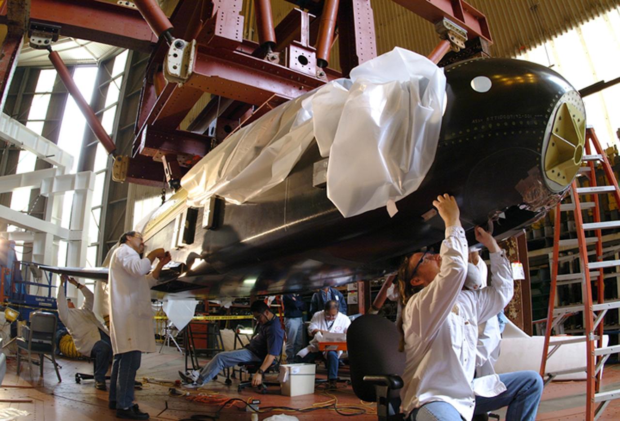 NASA's X-37 Approach and Landing Test Vehicle is installed is a structural facility at Boeing's Huntington Beach, California plant, where technicians make adjustments to composite panels. Tests, completed in July, were conducted to verify the structural integrity of the vehicle in preparation for atmospheric flight tests. Atmospheric flight tests of the Approach and Landing Test Vehicle are scheduled for 2004 and flight tests of the Orbital Vehicle are scheduled for 2006. The X-37 experimental launch vehicle is roughly 27.5 feet (8.3 meters) long and 15 feet (4.5 meters) in wingspan. It's experiment bay is 7 feet (2.1 meters) long and 4 feet (1.2 meters) in diameter. Designed to operate in both the orbital and reentry phases of flight, the X-37 will increase both safety and reliability, while reducing launch costs from $10,000 per pound to $1,000.00 per pound. The X-37 program is managed by the Marshall Space Flight Center and built by the Boeing Company.