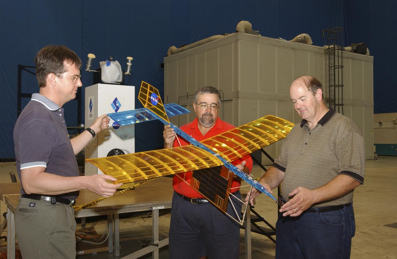 A team of NASA researchers from Marshall Space Flight Center (MSFC) and Dryden Flight Research center have proven that beamed light can be used to power an aircraft, a first-in-the-world accomplishment to the best of their knowledge. Using an experimental custom built radio-controlled model aircraft, the team has demonstrated a system that beams enough light energy from the ground to power the propeller of an aircraft and sustain it in flight. Special photovoltaic arrays on the plane, similar to solar cells, receive the light energy and convert it to electric current to drive the propeller motor. In a series of indoor flights this week at MSFC, a lightweight custom built laser beam was aimed at the airplane `s solar panels. The laser tracks the plane, maintaining power on its cells until the end of the flight when the laser is turned off and the airplane glides to a landing. The laser source demonstration represents the capability to beam more power to a plane so that it can reach higher altitudes and have a greater flight range without having to carry fuel or batteries, enabling an indefinite flight time. The demonstration was a collaborative effort between the Dryden Center at Edward's, California, where the aircraft was designed and built, and MSFC, where integration and testing of the laser and photovoltaic cells was done. Laser power beaming is a promising technology for consideration in new aircraft design and operation, and supports NASA's goals in the development of revolutionary aerospace technologies. Photographed with their invention are (from left to right): David Bushman and Tony Frackowiak, both of Dryden; and MSFC's Robert Burdine.