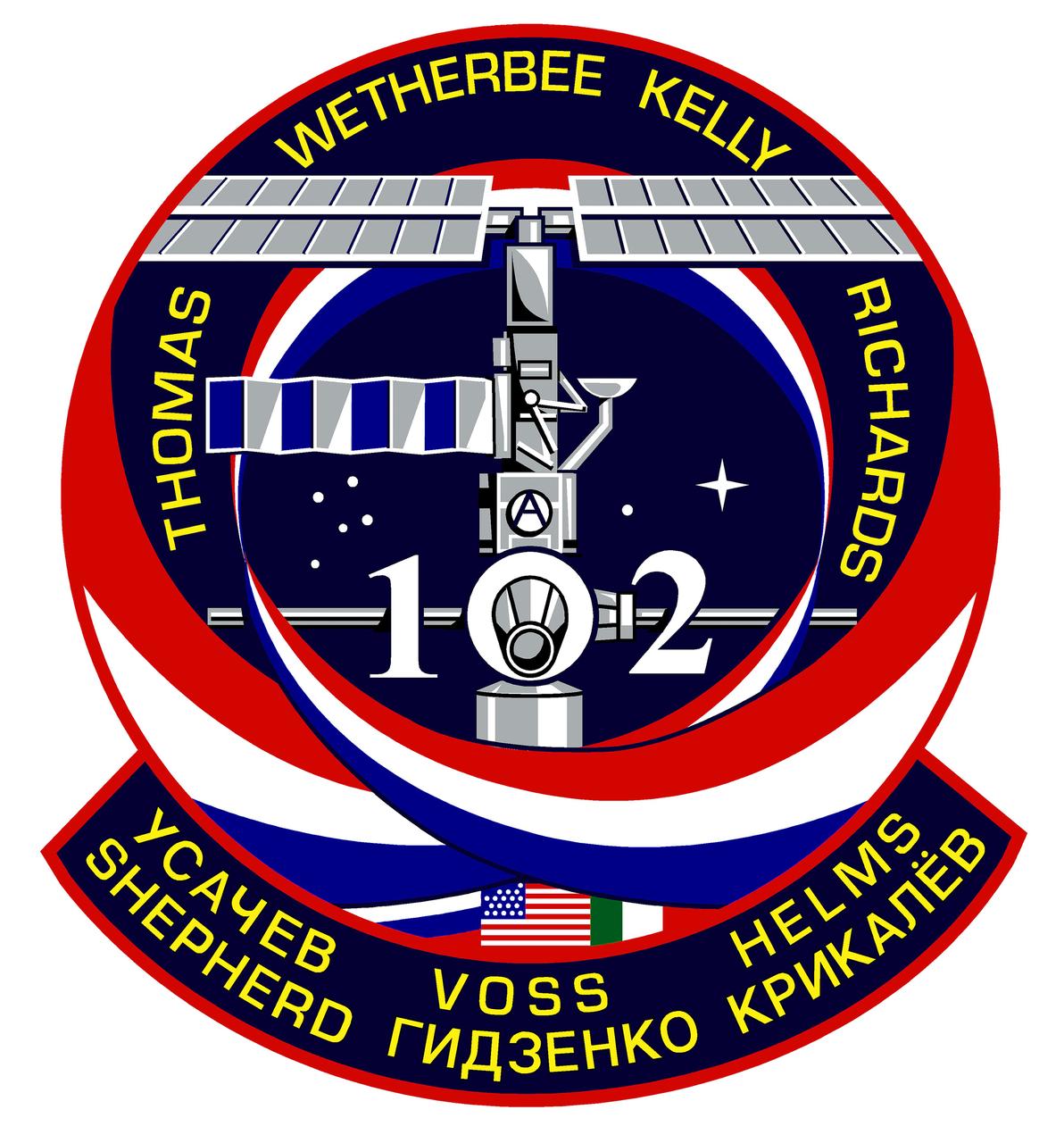 This is the STS-102 mission crew insignia. The central image on the crew patch depicts the International Space Station (ISS) in the build configuration that it had at the time of the arrival and docking of Discovery during the STS-102 mission, the first crew exchange flight to the Space Station. The station is shown along the direction of the flight as was seen by the shuttle crew during their final approach and docking, the so-called V-bar approach. The names of the shuttle crew members are depicted in gold around the top of the patch, and surnames of the Expedition crew members being exchanged are shown in the lower barner. The three ribbons swirling up to and around the station signify the rotation of these ISS crew members. The number 2 is for the Expedition 2 crew who flew up to the station, and the number 1 is for the Expedition 1 crew who then returned down to Earth. In conjunction with the face of the Lab module of the Station, these Expedition numbers create the shuttle mission number 102. Shown mated below the ISS is the Italian-built Multipurpose Logistics Module, Leonardo, that flew for the first time on this flight. The flags of the countries that were the major contributors to this effort, the United States, Russia, and Italy are also shown in the lower part of the patch. The build-sequence number of this flight in the overall station assembly sequence, 5A.1, is captured by the constellations in the background.