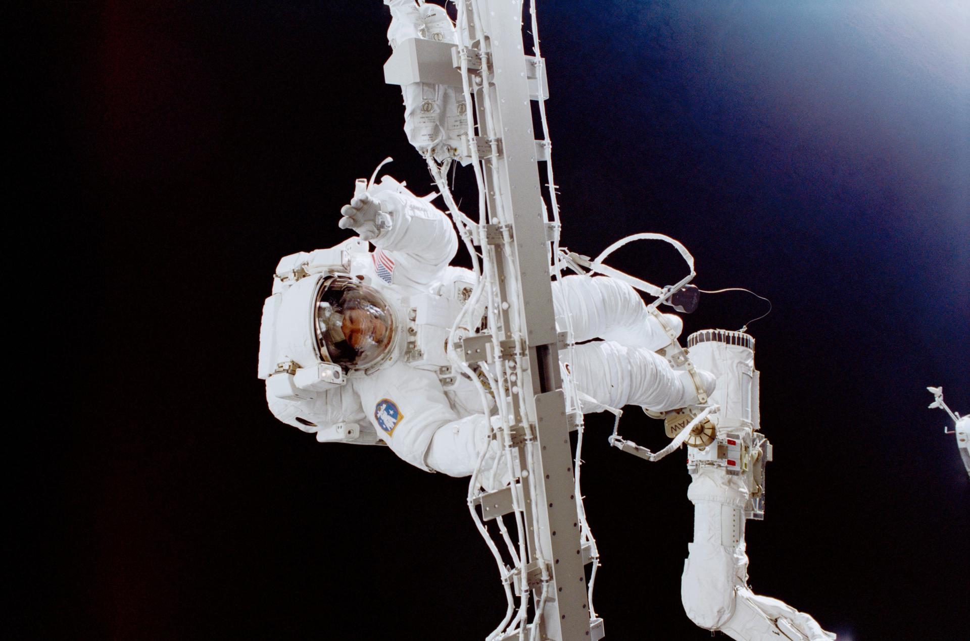 Astronaut Susan Helms works outside the International Space Station while attached to the Canadarm robotic arm on the Space Shuttle Discovery during a spacewalks.