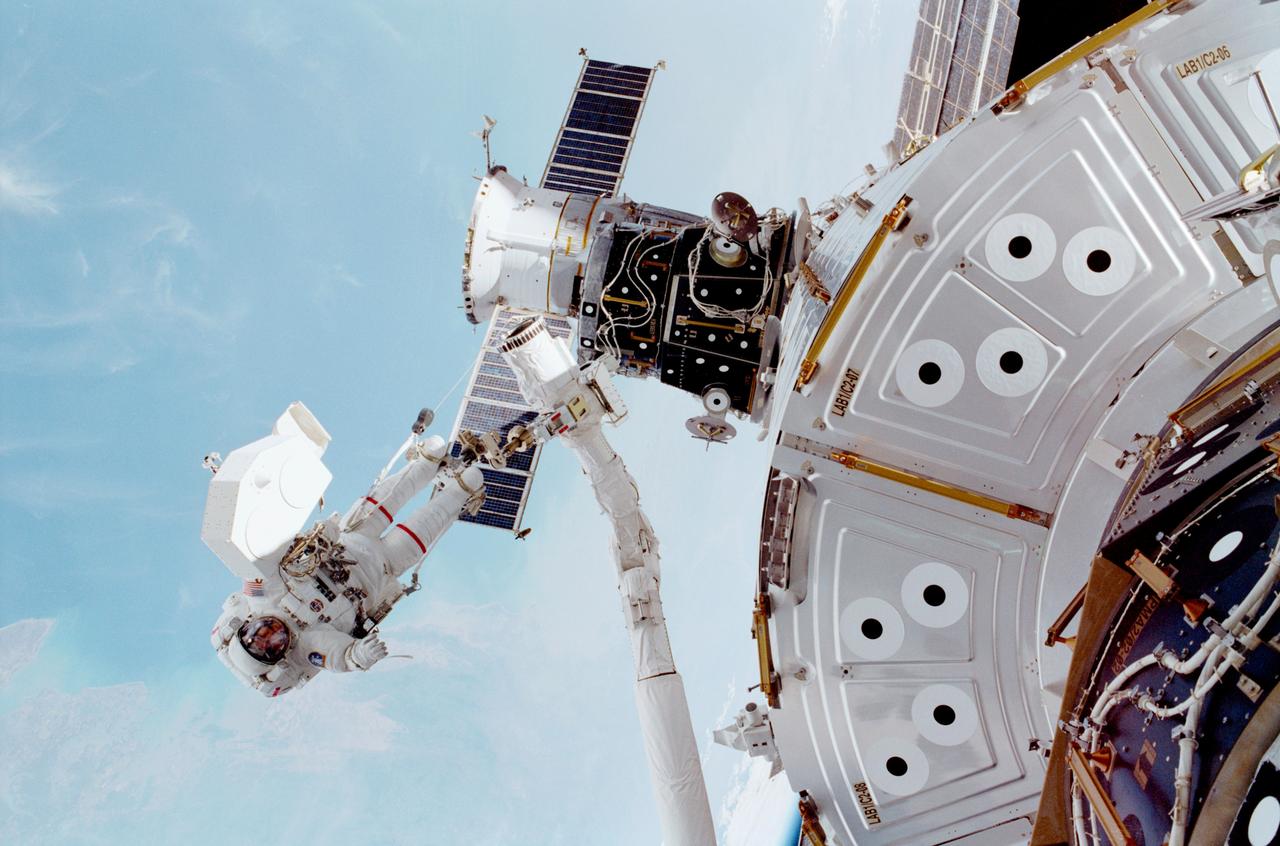 STS-102 astronaut and mission specialist James S. Voss works outside Destiny, the U.S. Laboratory (shown in lower frame) on the International Space Station (ISS), while anchored to the Remote Manipulator System (RMS) robotic arm on the Space Shuttle Discovery during the first of two space walks. During this space walk, the longest to date in space shuttle history, Voss in tandem with Susan Helms (out of frame), prepared the Pressurized Mating Adapter 3 for repositioning from the Unity Module's Earth-facing berth to its port-side berth to make room for the Leonardo Multipurpose Logistics Module (MPLM) supplied by the Italian Space Agency. The The Leonardo MPLM is the first of three such pressurized modules that will serve as the ISS' moving vans, carrying laboratory racks filled with equipment, experiments, and supplies to and from the Station aboard the Space Shuttle. The cylindrical module is approximately 21-feet long and 15- feet in diameter, weighing almost 4.5 tons. It can carry up to 10 tons of cargo in 16 standard Space Station equipment racks. Of the 16 racks the module can carry, 5 can be furnished with power, data, and fluid to support refrigerators or freezers. In order to function as an attached station module as well as a cargo transport, the logistics module also includes components that provide life support, fire detection and suppression, electrical distribution, and computer functions. Launched on May 8, 2001 for nearly 13 days in space, the STS-102 mission was the 8th spacecraft assembly flight to the ISS and NASA's 103rd overall mission. The mission also served as a crew rotation flight. It delivered the Expedition Two crew to the Station and returned the Expedition One crew back to Earth.