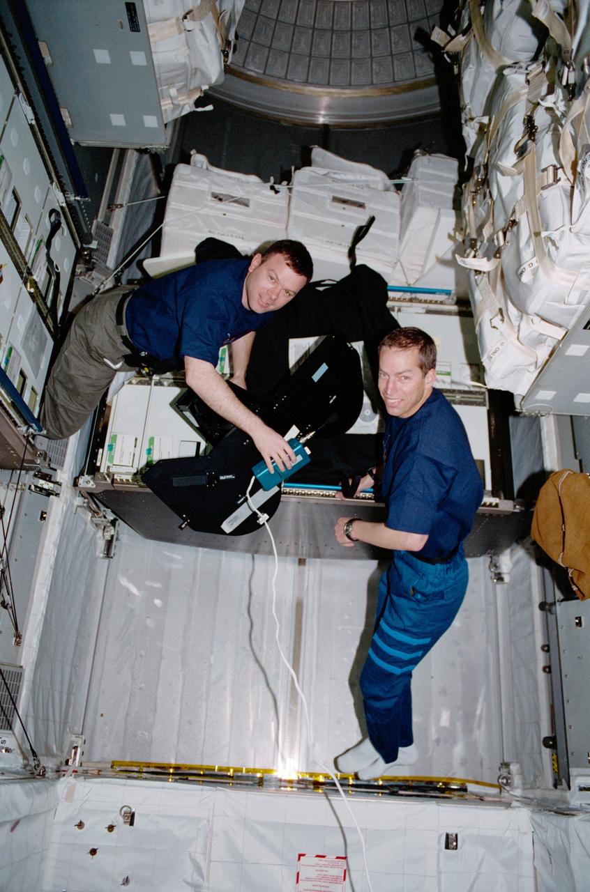 Pilot James M. Kelly (left) and Commander James D. Wetherbee for the STS-102 mission, participate in the movement of supplies inside Leonardo, the Italian Space Agency built Multipurpose Logistics Module (MPLM). In this particular photograph, the two are handling a film magazine for the IMAX cargo bay camera. The primary cargo of the STS-102 mission, the Leonardo MPLM is the first of three such pressurized modules that will serve as the International Space Station's (ISS') moving vans, carrying laboratory racks filled with equipment, experiments, and supplies to and from the Station aboard the Space Shuttle. The cylindrical module is approximately 21-feet long and 15- feet in diameter, weighing almost 4.5 tons. It can carry up to 10 tons of cargo in 16 standard Space Station equipment racks. Of the 16 racks the module can carry, 5 can be furnished with power, data, and fluid to support refrigerators or freezers. In order to function as an attached station module as well as a cargo transport, the logistics module also includes components that provide life support, fire detection and suppression, electrical distribution, and computer functions. The eighth station assembly flight, the STS-102 mission also served as a crew rotation flight. It delivered the Expedition Two crew to the Station and returned the Expedition One crew back to Earth.
