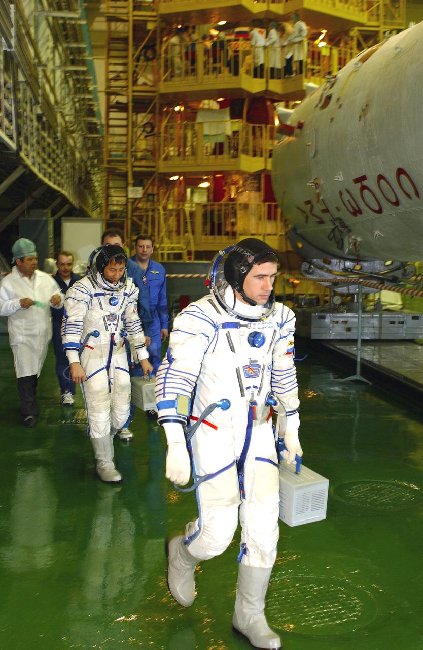 April 10, 2003.  Baikonur Cosmodrome, Kazakhstan. Building 254, Soyuz Integration Facility.  Cosmonaut Yuri I. Malenchenko (forground), Expedition Seven commander and Astronaut Edward T. Lu, NASA ISS science officer and flight engineer walk out for Soyuz inspection, seat liner check. The Soyuz is in the workstand in the background.  Photo Credit: "NASA/Bill Ingalls"