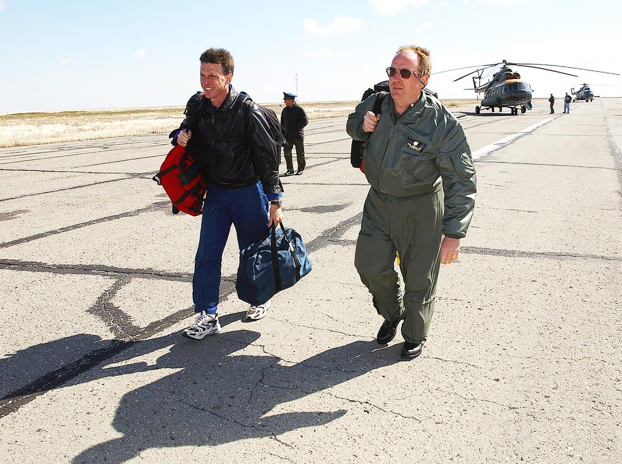 May 4, 2003, Kazakhstan. Astronaut Michael Foale (L) and Mike Duncan (R), Expedition Six Lead Flight Surgeon move to the lead helicopter after the landing team helicopters needed to return for refueling. Foale and Duncan went on from the refueling to meet the crew of Expedition Six at the landing site. Photo Credit: "NASA/Bill Ingalls"