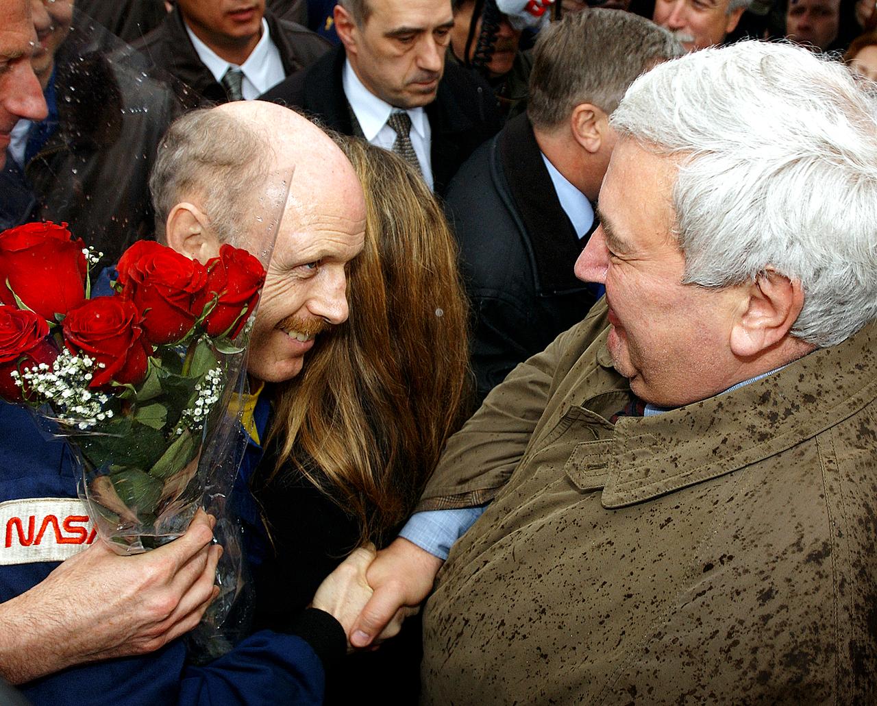 May 4, 2003, Star City, Russia. Russian Space Agency Director Yuri Koptev shakes hands with Expedition Six Commander Ken Bowersox, as bowersox is also hugged by his wife Annie. Photo Credit: "NASA/Bill Ingalls"