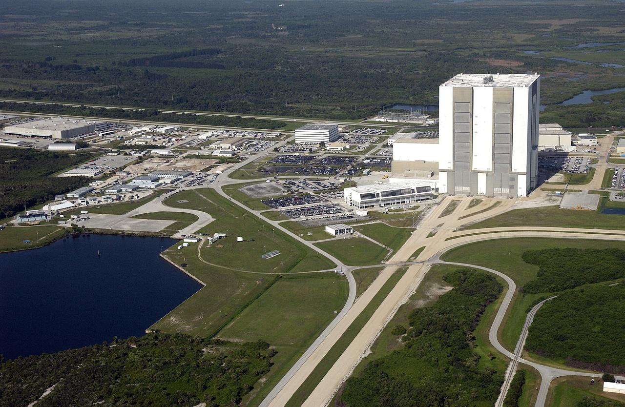 KENNEDY SPACE CENTER, FLA. – Looking west, this aerial view shows the crawlerway leading to the 525-foot-tall Vehicle Assembly Building. At left of the VAB is the Launch Control Center. Further to the left and west is the Operations Support Building. In the foreground at left is the Turn Basin, where external tanks are offloaded for transfer to the VAB.