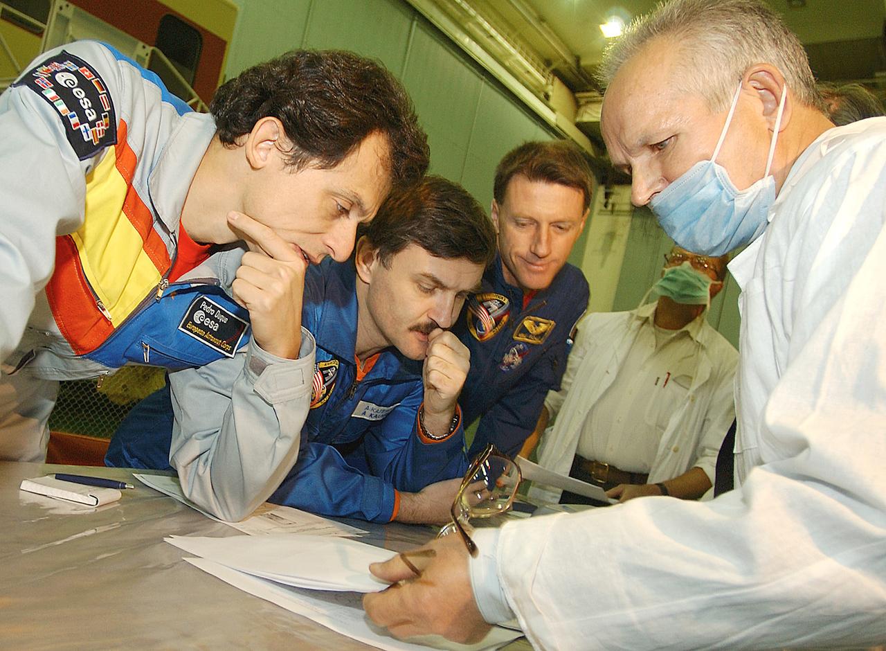 October 13, 2003.  Baikonur Cosmodrome, Kazakhstan. European Space Agency Astronaut Pedro Duque of Spain (left), Expedition 8 Soyuz Commander Alexander Kaleri (center) and Expedition 8 Commander and NASA Science Officer Mike Foale (right) receive a briefing on the operation of a satellite phone during prelaunch training Oct. 13, 2003 at the Baikonur Cosmodrome in Kazakhstan. The trio will be launched to the International Space Station on a Soyuz TMA-3 vehicle on Oct. 18.  Photo Credit"NASA/Bill Ingalls"
