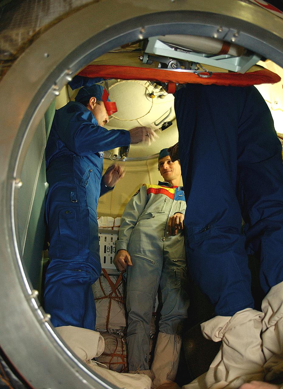 October 13, 2003.  Baikonur Cosmodrome, Kazakhstan. Inside the Soyuz TMA-3 vehicle, Expedition 8 Soyuz Commander Alexander Kaleri (left) briefs European Space Agency Astronaut Pedro Duque of Spain and Expedition 8 Commander and NASA Science Officer Mike Foale (right, partially hidden) during a prelaunch inspection of the spacecraft at the Baikonur Cosmodrome in Kazakhstan Oct. 13, 2003. The trio will be launched to the International Space Station on Oct. 18.  Photo Credit"NASA/Bill Ingalls"