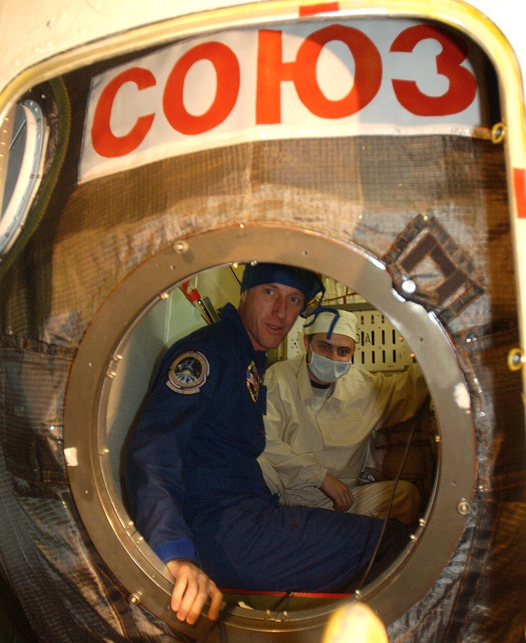 October 13, 2003. Baikonur Cosmodrome, Kazakhstan. Expedition 8 Commander and NASA Science Officer Mike Foale (left) is briefed by a technician (right) inside the Soyuz TMA-3 vehicle in a processing facility at the Baikonur Cosmodrome in Kazakhstan on Oct. 13, 2003 during an inspection of the spacecraft. Foale, Expedition 8 Soyuz Commander Alexander Kaleri (center) and European Space Agency Astronaut Pedro Duque of Spain will be launched in the Soyuz Oct. 18 to the International Space Station. Photo Credit"NASA/Bill Ingalls"