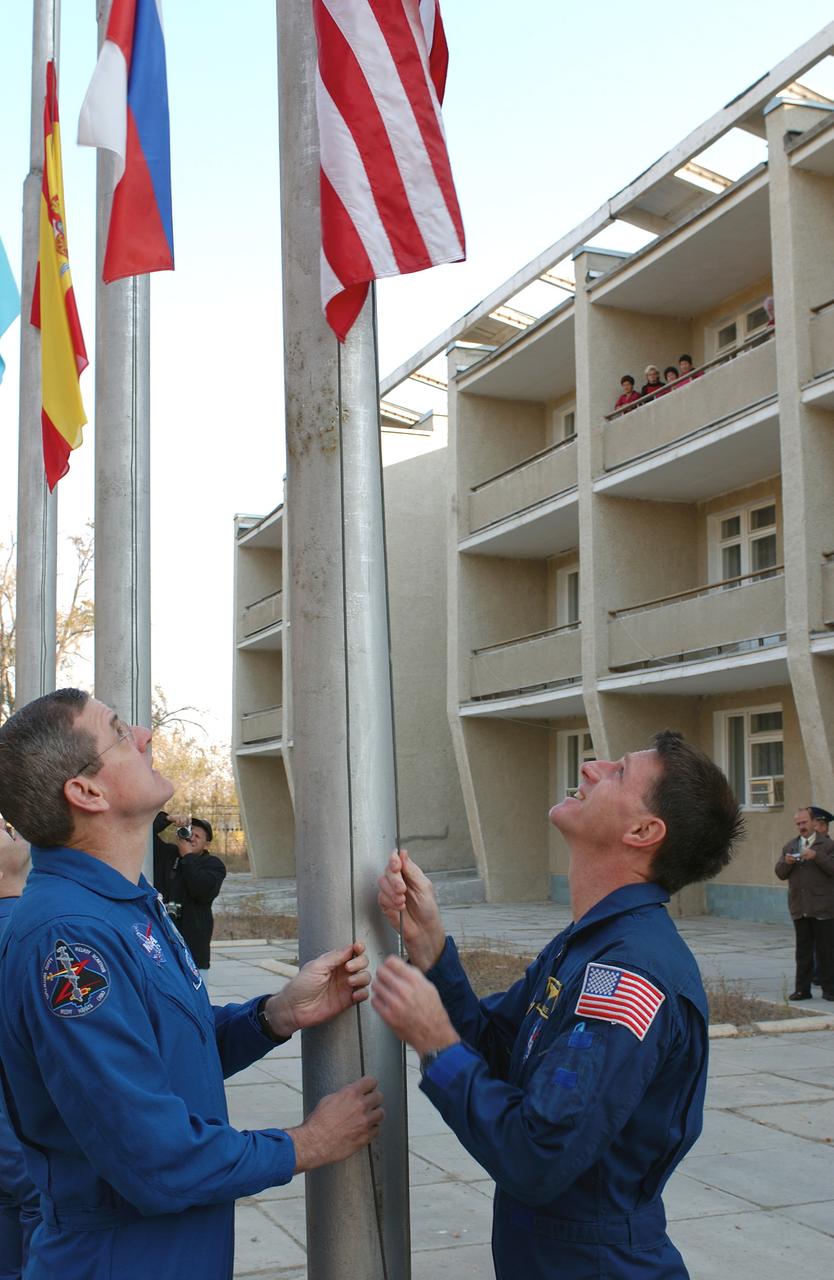 October 14, 2003. Cosmonaut Hotel, Baikonur, Kazakhstan. Backup Expedition 8 Commander and NASA Science Officer Bill McArthur (left) and prime Expedition 8 Commander and NASA Science Officer Mike Foale raise the American flag outside the Cosmonaut Hotel Oct. 14, 2003 in a traditional ceremony as preparations continue for the launch Saturday of the Soyuz TMA-3 vehicle from the Baikonur Cosmodrome to carry Foale, Expedition 8 Soyuz commander Alexander Kaleri and European Space Agency Astronaut Pedro Duque to the International Space Station.. Photo Credit: "NASA/Bill Ingalls"
