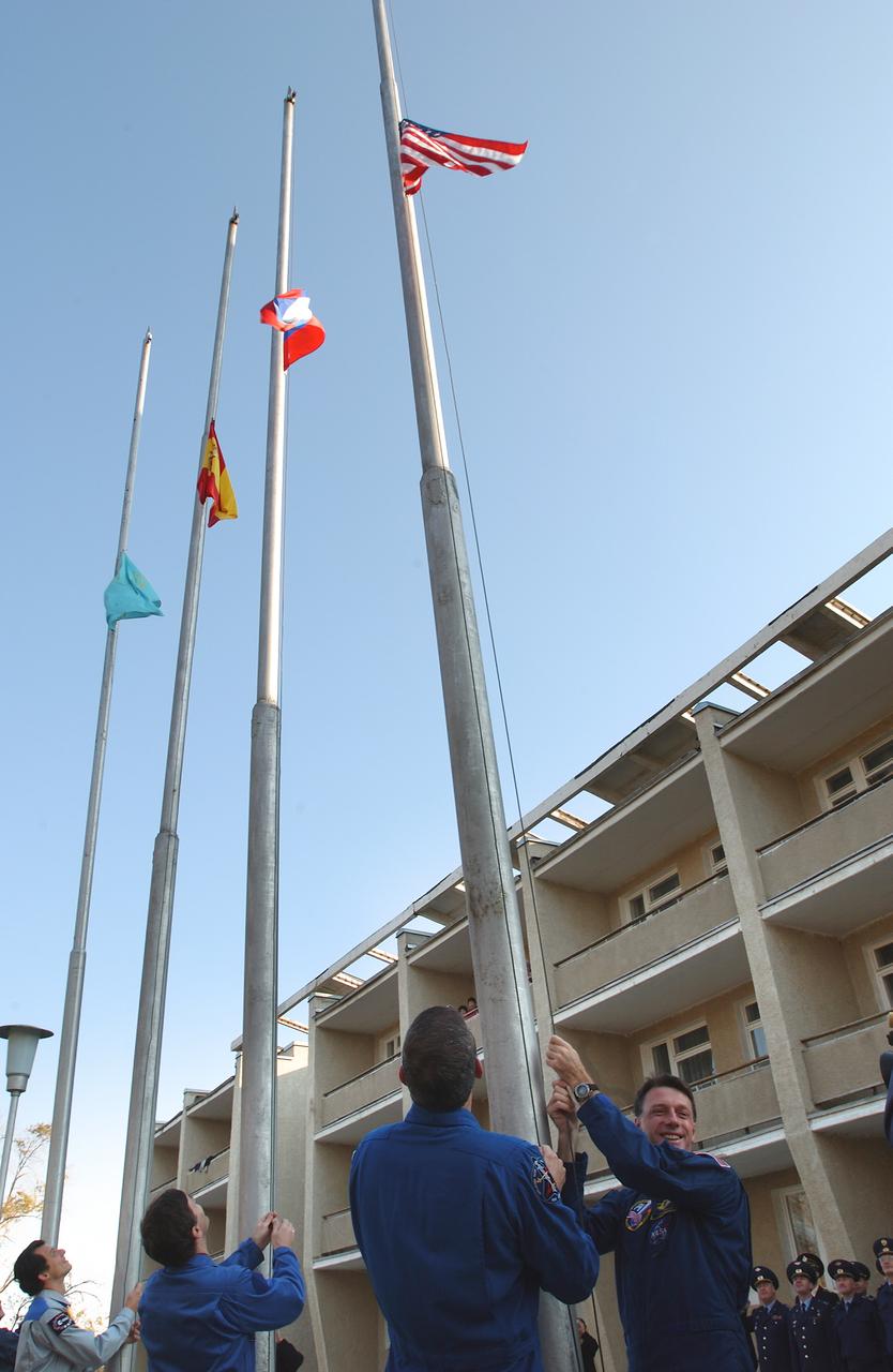 October 14, 2003. Cosmonaut Hotel, Baikonur, Kazakhstan. Expedition 8 Commander and NASA Science Officer Mike Foale (right) is joined by his backup, Bill McArthur outside the Cosmonaut Hotel Oct. 14, 2003 for the traditional raising of the flags of the crewmembers who will launch Saturday on the Soyuz TMA-3 vehicle to the International Space Station. European Space Agency Astronaut Pedro Duque (left) and Expedition 8 Soyuz Commander Alexander Kaleri (second from left), who will launch with Foale, raise the flags of Spain and Russia outside their hotel.. Photo Credit: "NASA/Bill Ingalls"