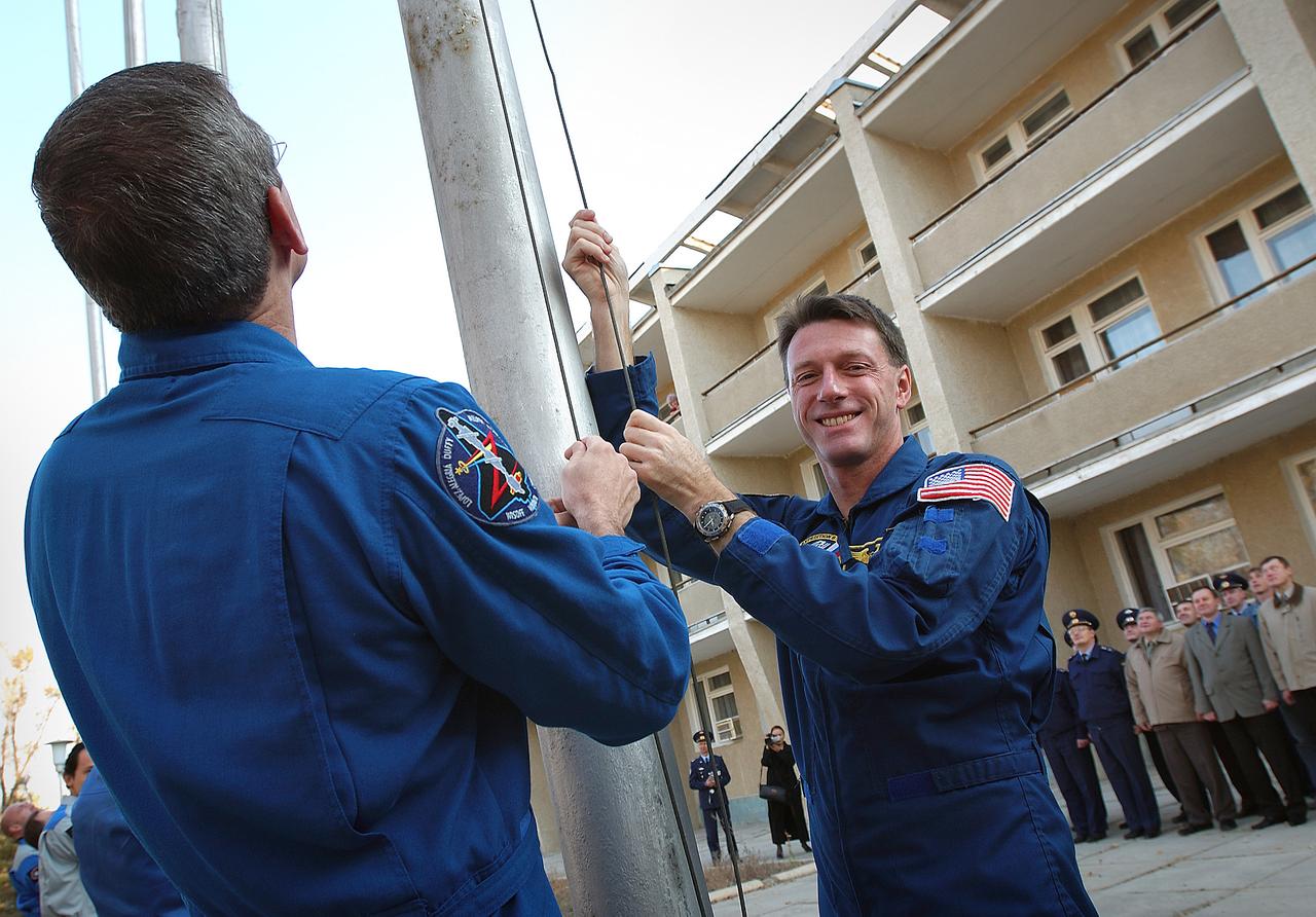 October 14, 2003. Cosmonaut Hotel, Baikonur, Kazakhstan. Backup Expedition 8 Commander and NASA Science Officer Bill McArthur (left) and prime Expedition 8 Commander and NASA Science Officer Mike Foale raise the American flag outside the Cosmonaut Hotel Oct. 14, 2003 in a traditional ceremony as preparations continue for the launch Saturday of the Soyuz TMA-3 vehicle from the Baikonur Cosmodrome to carry Foale, Expedition 8 Soyuz commander Alexander Kaleri and European Space Agency Astronaut Pedro Duque to the International Space Station. Photo Credit: "NASA/Bill Ingalls"