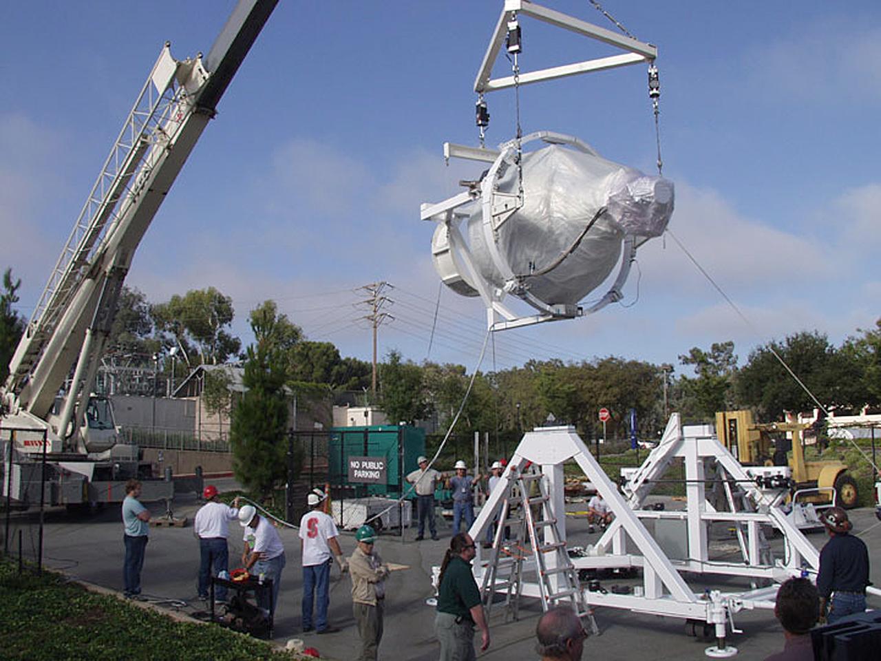 The Gravity Probe B (GP-B) payload was hoisted by crane to the transportation truck in the W.W. Hansen Experimental Physics Laboratory in Stanford, California for shipment to the launch site at Vandenburg Air Force Base. GP-B is the relativity experiment being developed at Stanford University to test two extraordinary predictions of Albert Einstein’s general theory of relativity. The experiment will measure, very precisely, the expected tiny changes in the direction of the spin axes of four gyroscopes contained in an Earth-orbiting satellite at a 400-mile altitude. So free are the gyroscopes from disturbance that they will provide an almost perfect space-time reference system. They will measure how space and time are very slightly warped by the presence of the Earth, and, more profoundly, how the Earth’s rotation very slightly drags space-time around with it. These effects, though small for the Earth, have far-reaching implications for the nature of matter and the structure of the Universe. GP-B is among the most thoroughly researched programs ever undertaken by NASA. This is the story of a scientific quest in which physicists and engineers have collaborated closely over many years. Inspired by their quest, they have invented a whole range of technologies that are already enlivening other branches of science and engineering. Launched April 20, 2004, the GP-B program was managed for NASA by the Marshall Space Flight Center. Development of the GP-B is the responsibility of Stanford University, along with major subcontractor Lockheed Martin Corporation. (Photo Credit: Stanford University)