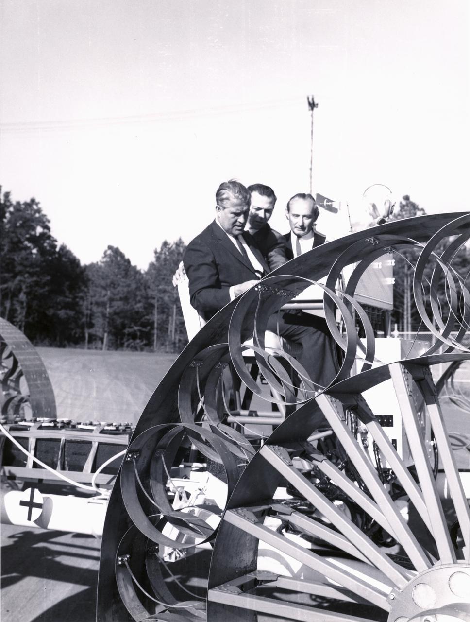 Marshall Space Flight Center (MSFC) director, Wernher von Braun, and others examine one concept of a possible Lunar Roving Vehicle (LRV) built by the Bendix Corporation.  The data provided by the MTA helped in designing the LRV, developed under the direction of MSFC. The LRV was designed to allow Apollo astronauts a greater range of mobility during lunar exploration missions. 