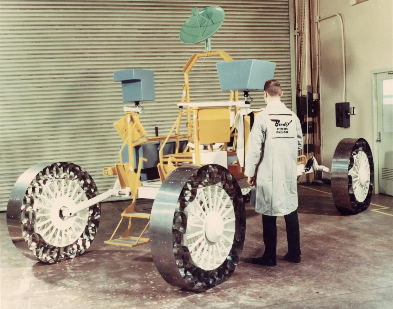 A concept of a possible Lunar Roving Vehicle (LRV) built by the Bendix Corporation for NASA’s Marshall Space Flight Center (MSFC). This Mobility Test Article (MTA) is being inspected by a Bendix technician. The data provided by the MTA helped in designing the LRV, developed under the direction of MSFC. The LRV was designed to allow Apollo astronauts a greater range of mobility during lunar exploration missions. 