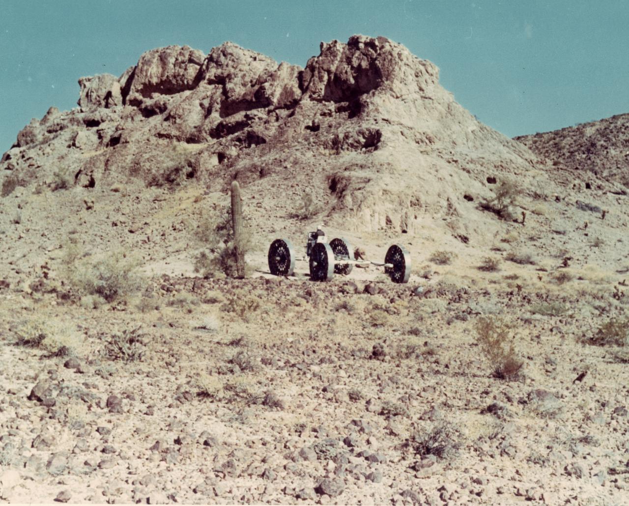 A test engineer drives a Mobility Test Article (MTA) during a test of a Lunar Roving Vehicle (LRV) concept through the mountains of Arizona. The data provided by the MTA helped in designing the LRV, developed under the direction of MSFC. The LRV was designed to allow Apollo astronauts a greater range of mobility during lunar exploration missions. 