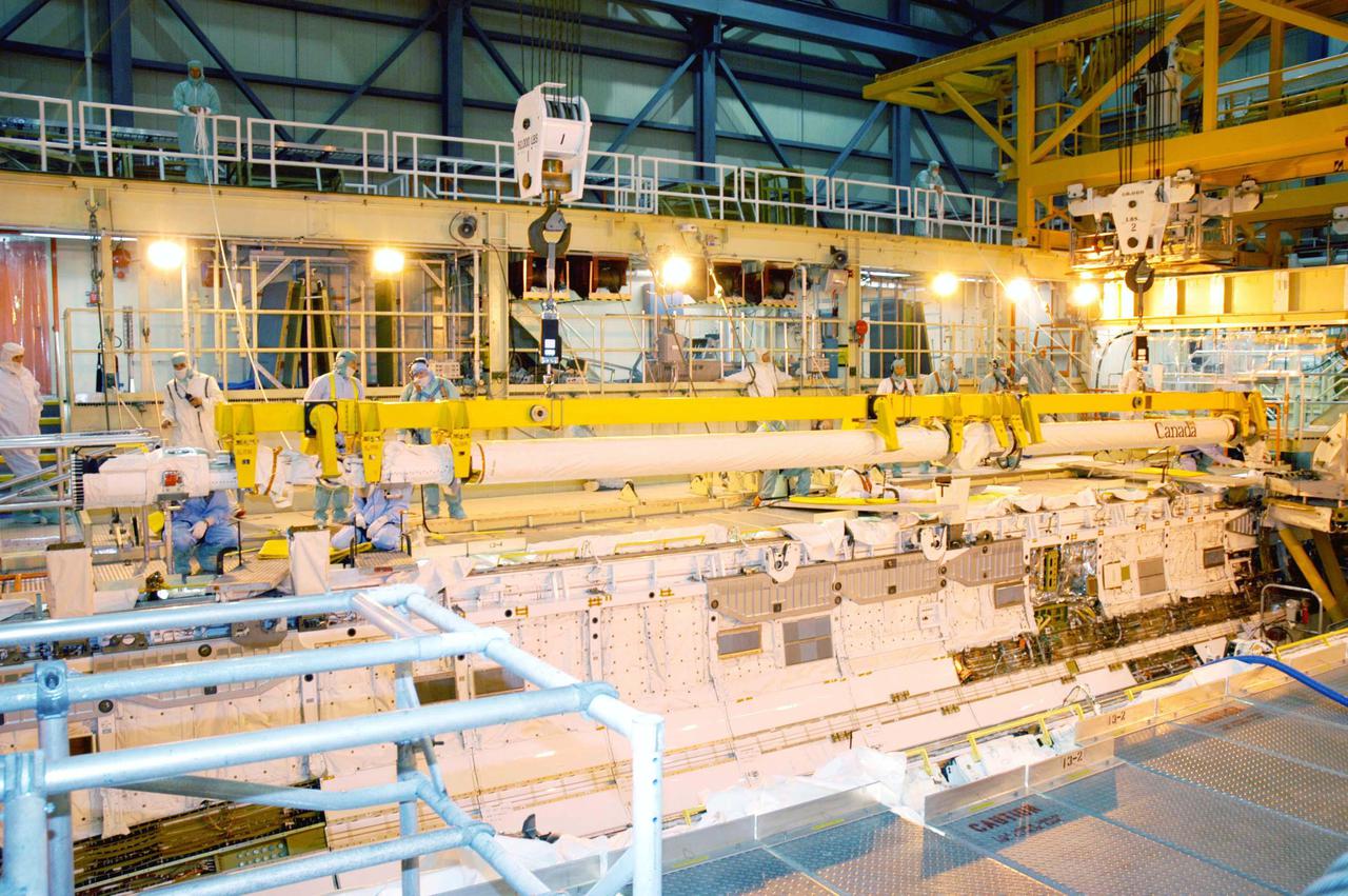 KENNEDY SPACE CENTER, FLA. - In the Orbiter Processing Facility, the Remote Manipulator System (RMS), also known as the Canadian robotic arm, is moved toward Discovery’s payload bay for installation. The RMS is used to deploy and retrieve payloads, provide a mobile extension ladder or foot restraints for crew members during extravehicular activities; and to aid the flight crew members in viewing surfaces of the orbiter or payloads through a television camera on the RMS. The arm is also serving as the base for the new Orbiter Boom Sensor System (OBSS), one of the safety measures for Return to Flight, equipping the Shuttle with cameras and laser systems to inspect the Shuttle’s Thermal Protection System while in space.  Discovery is scheduled for a launch planning window of May 2005 on Return to Flight mission STS-114.
