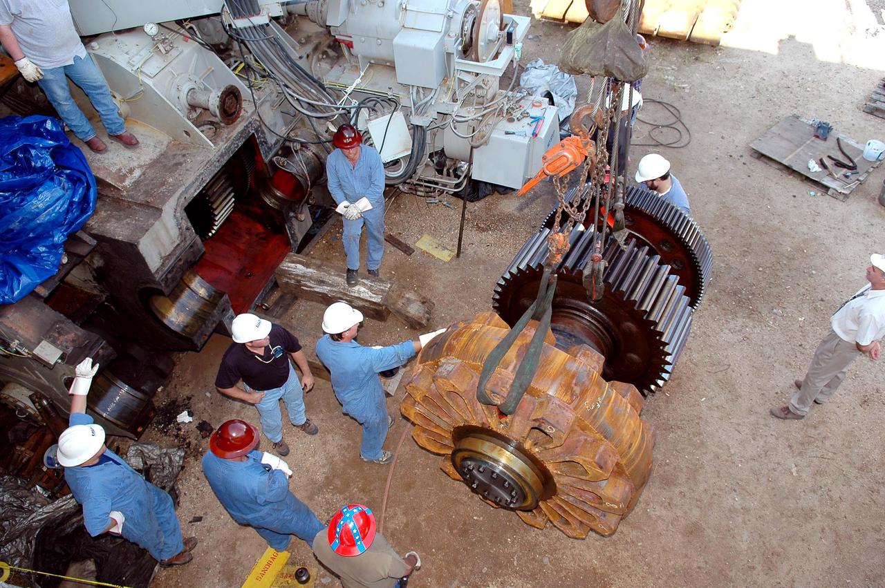 KENNEDY SPACE CENTER, FLA. -   Workers get ready to install the giant-sized sprocket (left side) and gear (right side) on the Crawler-Transporter at left.  The drive sprocket turns the belt on the CT.  The sprocket is mated to the gear that attaches to the drive motor.  The CT travels on eight tracked tread belts, each containing 57 tread belt shoes, for a combined weight of 957,600 pounds.  The CT carries the Space Shuttle atop its Mobile Launcher Platform, adding another 12 million pounds, from the Vehicle Assembly Building to the launch pad.  NASA and United Space Alliance (USA) CT system engineers and USA technicians are repairing the sprockets and rollers on each belt before new shoes are installed.  Replacement of the sprockets, gears and shoes is part of the most extensive maintenance work performed on the CT in its history.