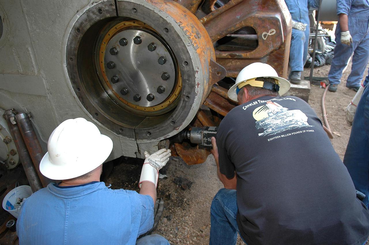 KENNEDY SPACE CENTER, FLA. -   Workers attach the giant sprocket and attached gear onto the Crawler-Transporter.  The drive sprocket turns the belt on the CT.  The sprocket is mated to the gear that attaches to the drive motor.  The CT travels on eight tracked tread belts, each containing 57 tread belt shoes, for a combined weight of 957,600 pounds.  The CT carries the Space Shuttle atop its Mobile Launcher Platform, adding another 12 million pounds, from the Vehicle Assembly Building to the launch pad.  NASA and United Space Alliance (USA) CT system engineers and USA technicians are repairing the sprockets and rollers on each belt before new shoes are installed.  Replacement of the sprockets, gears and shoes is part of the most extensive maintenance work performed on the CT in its history.