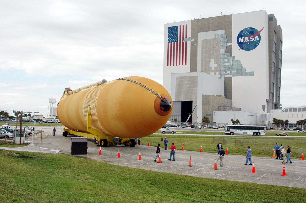KENNEDY SPACE CENTER, FLA. -   KSC workers escort External Tank 118 (ET-118) from the Vehicle Assembly Building, in the background, to the barge in the Turn Basin at Launch Complex 39. The tank will be transported to NASA’s Michoud Assembly Facility in New Orleans.  The tank is being installed with an improved bipod fitting, which connects the external fuel tank to the Shuttle during launch. The new design, a significant milestone in the effort to return the Shuttle to safe flight, replaces the foam that was used to prevent ice buildup on the tank’s bipod fittings with four rod-shaped heaters.  The heaters are being retrofitted on the 11 existing tanks and incorporated into the manufacture of all new tanks.