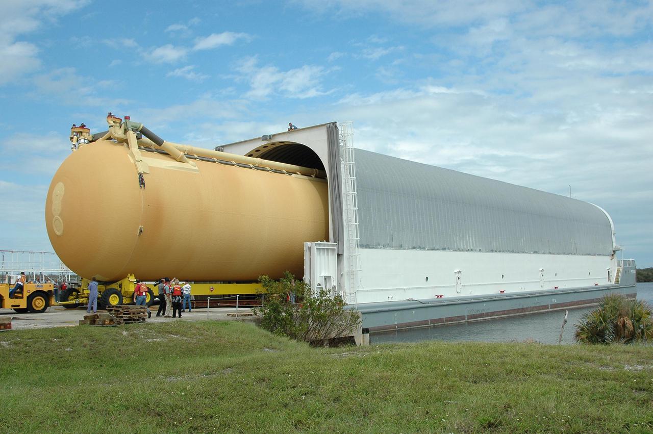 KENNEDY SPACE CENTER, FLA. - At the Turn Basin in Launch Complex 39, External Tank 118 (ET-118) enters the barge that will transport it to NASA’s Michoud Assembly Facility in New Orleans. It had been stored in the Vehicle Assembly Building. The tank is being installed with an improved bipod fitting, which connects the external fuel tank to the Shuttle during launch. The new design, a significant milestone in the effort to return the Shuttle to safe flight, replaces the foam that was used to prevent ice buildup on the tank’s bipod fittings with four rod-shaped heaters. The heaters are being retrofitted on the 11 existing tanks and incorporated into the manufacture of all new tanks.