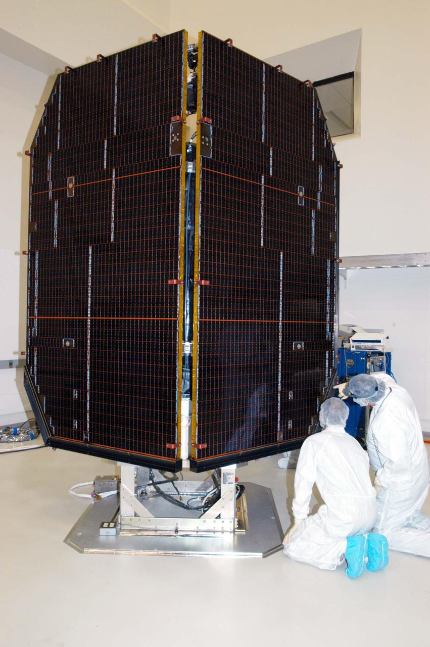 KENNEDY SPACE CENTER, FLA. - At Astrotech Space Operations in Titusville, Fla., Alec Baldwin (left) and Mike Renbarger check cells on the solar panels on the Deep Impact spacecraft. Baldwin is a technician and Renbarger a contamination control technician with Ball Aerospace and Technologies Corp. in Boulder, Colo. The spacecraft is undergoing verification testing after its long road trip from Colorado. A NASA Discovery mission, Deep Impact will probe beneath the surface of Comet Tempel 1 on July 4, 2005, when the comet is 83 million miles from Earth, and reveal the secrets of its interior. After releasing a 3- by 3-foot projectile to crash onto the surface, Deep Impact’s flyby spacecraft will collect pictures and data of how the crater forms, measuring the crater’s depth and diameter, as well as the composition of the interior of the crater and any material thrown out, and determining the changes in natural outgassing produced by the impact. It will send the data back to Earth through the antennas of the Deep Space Network. The spacecraft is scheduled to launch Dec. 30, 2004, aboard a Boeing Delta II rocket from Launch Complex 17 at Cape Canaveral Air Force Station, Fla.