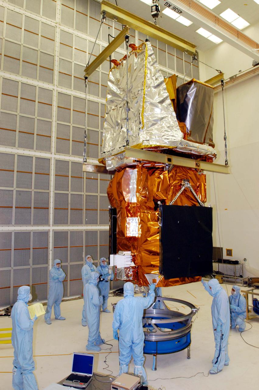 KENNEDY SPACE CENTER, FLA. - Technicians at NASA’s Hangar AE, Cape Canaveral Air Force Station (CCAFS), stand by while the Swift spacecraft is lowered toward a payload attach fitting, the interface between the spacecraft and the second stage of the Boeing Delta II rocket. Swift is a first-of-its-kind multi-wavelength observatory dedicated to the study of gamma-ray burst (GRB) science. Its three instruments will work together to observe GRBs and afterglows in the gamma ray, X-ray, ultraviolet and optical wavebands. Swift is expected to observe more than 200 gamma-ray bursts - the most comprehensive study of GRB afterglows to date - during its 2-year mission. Swift is scheduled to launch in November from Launch Pad 17-A at CCAFS.