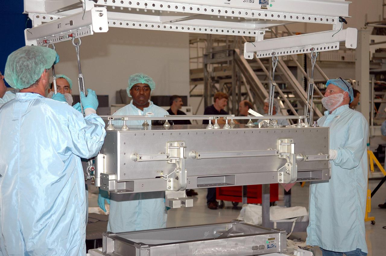 KENNEDY SPACE CENTER, FLA. -   Technicians at the Space Station Processing Facility prepare to lift and move a Thermal Protection System Sample Box onto the Lightweight Multi-Purpose Experiment Support Structure Carrier (LMC) for a fit check. The box is the actual flight hardware scheduled to fly on the Space Shuttle Return to Flight mission STS-114.  The fit check is performed to ensure the hardware mates properly with the newly modified LMC and will be returned to NASA’s Johnson Space Center for installation of tile samples in support of the STS-114 mission.  The Thermal Protection Detailed Test Objective will enable astronauts to test new on-orbit Thermal Protection System repair techniques.  Mission STS-114 is scheduled to launch in May 2005.