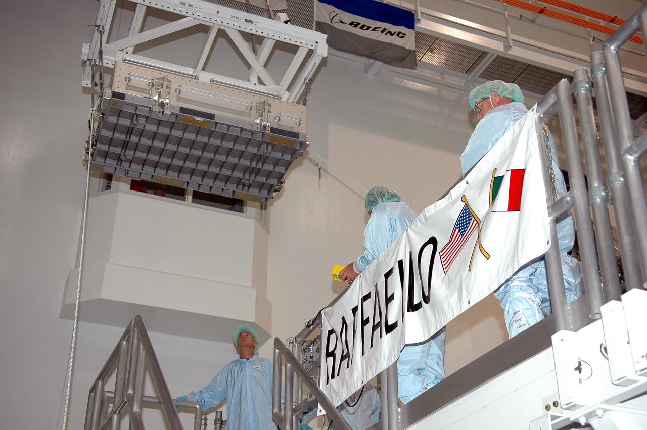KENNEDY SPACE CENTER, FLA. -   Technicians at the Space Station Processing Facility lower a Thermal Protection System Sample Box (upper left) toward the Lightweight Multi-Purpose Experiment Support Structure Carrier (LMC) for a fit check. The box is the actual flight hardware scheduled to fly on the Space Shuttle Return to Flight mission STS-114.  The fit check is performed to ensure the hardware mates properly with the newly modified LMC and will be returned to NASA’s Johnson Space Center for installation of tile samples in support of the STS-114 mission.  The Thermal Protection Detailed Test Objective will enable astronauts to test new on-orbit Thermal Protection System repair techniques.  Mission STS-114 is scheduled to launch in May 2005.