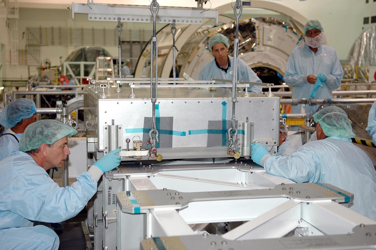 KENNEDY SPACE CENTER, FLA. -   Technicians at the Space Station Processing Facility perform a fit check of the Thermal Protection System Sample Box on the Lightweight Multi-Purpose Experiment Support Structure Carrier (LMC). The box is the actual flight hardware scheduled to fly on the Space Shuttle Return to Flight mission STS-114.  The fit check is performed to ensure the hardware mates properly with the newly modified LMC and will be returned to NASA’s Johnson Space Center for installation of tile samples in support of the STS-114 mission.  The Thermal Protection Detailed Test Objective will enable astronauts to test new on-orbit Thermal Protection System repair techniques.  Mission STS-114 is scheduled to launch in May 2005.
