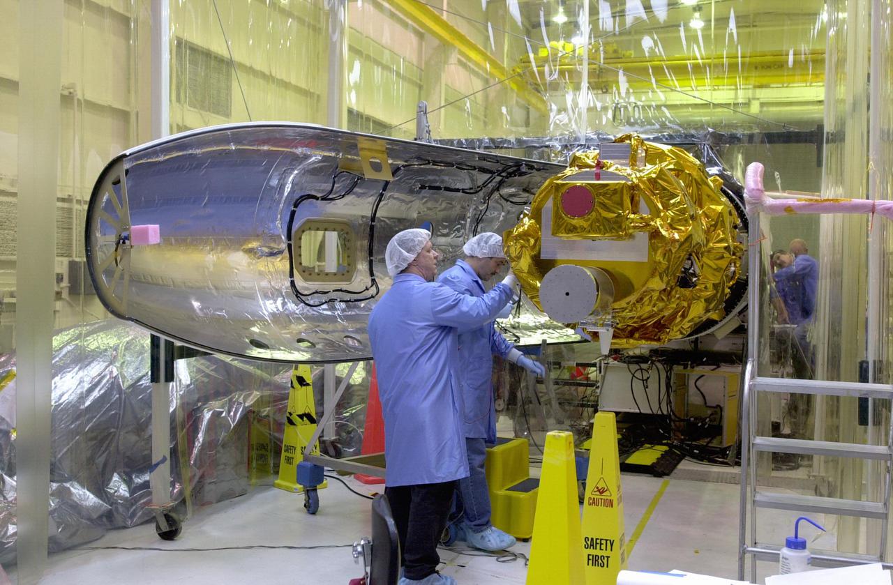 KENNEDY SPACE CENTER, FLA. - In preparation for launch, Orbital Sciences Corporation technicians at Vandenberg AFB in California get ready to place the first fairing half around the Demonstration of Autonomous Rendezvous Technology (DART) spacecraft. The fairing will encapsulate DART and protect it while on the launch pad and during ascent. DART was designed and built for NASA by Orbital Sciences as an advanced flight demonstrator to locate and maneuver near an orbiting satellite. The DART spacecraft weighs about 800 pounds and is nearly 6 feet long and 3 feet in diameter. From beneath the belly of the Orbital Sciences L-1011 aircraft, the Pegasus XL vehicle will launch DART into a circular polar orbit of approximately 475 miles. The DART satellite provides a key step in establishing autonomous rendezvous capabilities for the U.S. Space Program. While previous rendezvous and docking efforts have been piloted by astronauts, the unmanned DART satellite will have computers and cameras to perform its rendezvous functions.