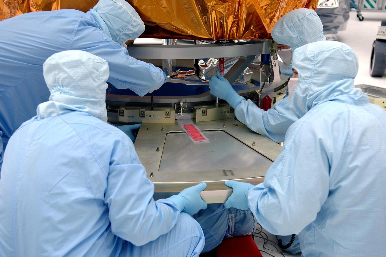 KENNEDY SPACE CENTER, FLA. - At NASA’s Hangar AE on Cape Canaveral Air Force Station (CCAFS), Fla., technicians attach the base petals of a transportation canister around the bottom of the payload attach fitting on the Swift spacecraft. Swift is a first-of-its-kind multi-wavelength observatory dedicated to the study of gamma-ray burst (GRB) science. Its three instruments will work together to observe GRBs and afterglows in the gamma ray, X-ray, ultraviolet and optical wavebands. Swift is expected to observe more than 200 gamma-ray bursts - the most comprehensive study of GRB afterglows to date - during its 2-year mission. Swift is scheduled to launch in mid-November from Launch Pad 17-A at CCAFS.