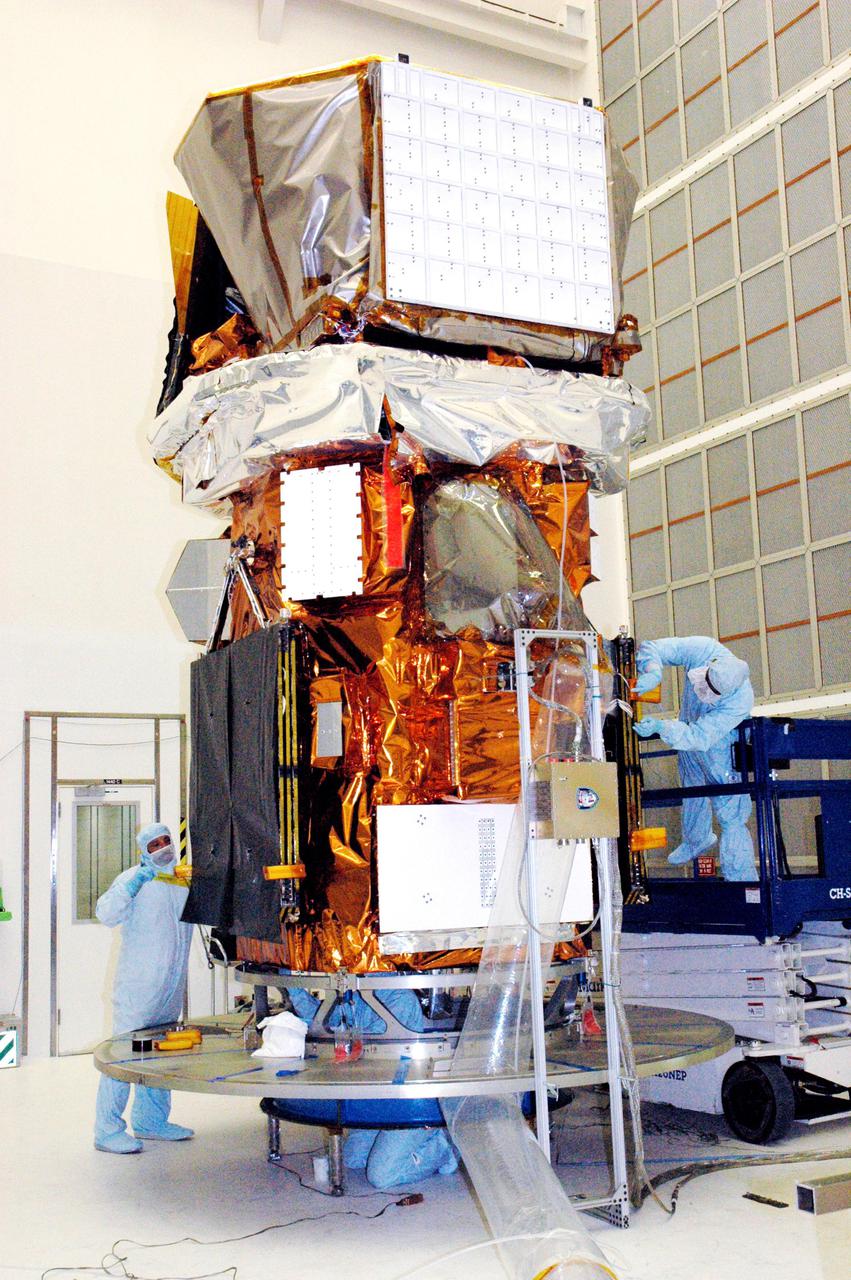 KENNEDY SPACE CENTER, FLA. - In Hangar AE at Cape Canaveral Air Force Station (CCAFS) in Florida, technicians with Spectrum Astro Inc. prepare to cover the Swift spacecraft with plastic before moving it to the launch pad. The launch of the Swift observatory, a NASA spacecraft to pinpoint the location of gamma-ray bursts, is scheduled for Nov. 17 from Pad 17-A on CCAFS. Liftoff aboard a Boeing Delta II rocket is targeted at the opening of a one-hour launch window beginning at 12:09 p.m. EST. Gamma-ray bursts are distant, yet fleeting explosions that appear to signal the births of black holes. They are the most powerful explosions known in the universe, emitting more than 100 billion times the energy that the Sun emits in a year. Yet they last only from a few milliseconds to a few minutes, never to appear in the same spot again.