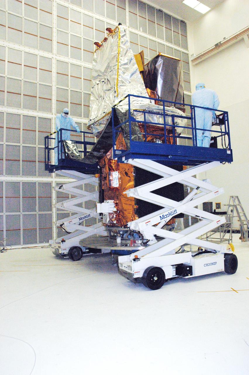 KENNEDY SPACE CENTER, FLA. - In Hangar AE at Cape Canaveral Air Force Station (CCAFS) in Florida, technicians with Spectrum Astro Inc. prepare to cover the Swift spacecraft with plastic before moving it to the launch pad. The launch of the Swift observatory, a NASA spacecraft to pinpoint the location of gamma-ray bursts, is scheduled for Nov. 17 from Pad 17-A on CCAFS. Liftoff aboard a Boeing Delta II rocket is targeted at the opening of a one-hour launch window beginning at 12:09 p.m. EST. Gamma-ray bursts are distant, yet fleeting explosions that appear to signal the births of black holes. They are the most powerful explosions known in the universe, emitting more than 100 billion times the energy that the Sun emits in a year. Yet they last only from a few milliseconds to a few minutes, never to appear in the same spot again.