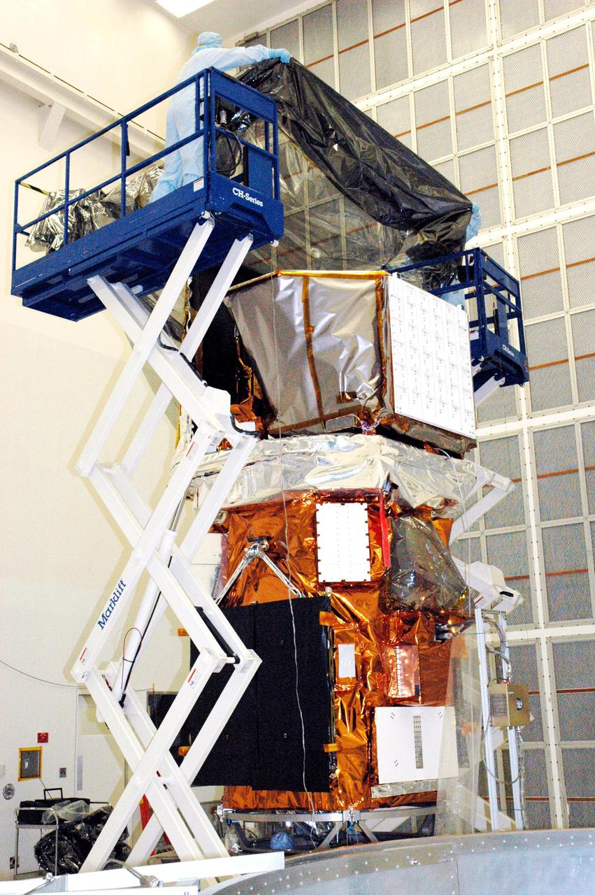 KENNEDY SPACE CENTER, FLA. - In Hangar AE at Cape Canaveral Air Force Station (CCAFS) in Florida, technicians with Spectrum Astro Inc. prepare to lower the protective cover over the Swift spacecraft before moving it to the launch pad. The launch of the Swift observatory, a NASA spacecraft to pinpoint the location of gamma-ray bursts, is scheduled for Nov. 17 from Pad 17-A on CCAFS. Liftoff aboard a Boeing Delta II rocket is targeted at the opening of a one-hour launch window beginning at 12:09 p.m. EST. Gamma-ray bursts are distant, yet fleeting explosions that appear to signal the births of black holes. They are the most powerful explosions known in the universe, emitting more than 100 billion times the energy that the Sun emits in a year. Yet they last only from a few milliseconds to a few minutes, never to appear in the same spot again.