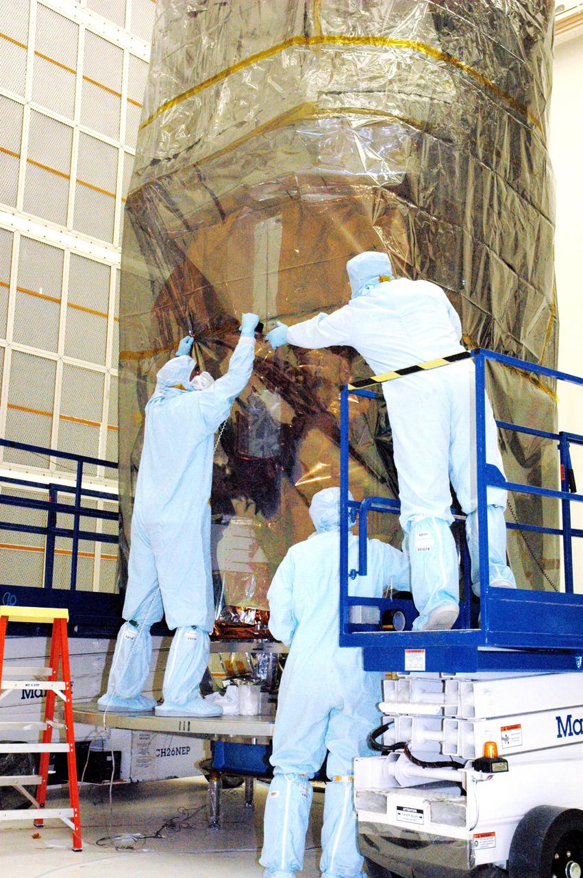 KENNEDY SPACE CENTER, FLA. - In Hangar AE at Cape Canaveral Air Force Station (CCAFS) in Florida, technicians with Spectrum Astro Inc. secure the plastic cover around the Swift spacecraft before moving it to the launch pad. The launch of the Swift observatory, a NASA spacecraft to pinpoint the location of gamma-ray bursts, is scheduled for Nov. 17 from Pad 17-A on CCAFS. Liftoff aboard a Boeing Delta II rocket is targeted at the opening of a one-hour launch window beginning at 12:09 p.m. EST. Gamma-ray bursts are distant, yet fleeting explosions that appear to signal the births of black holes. They are the most powerful explosions known in the universe, emitting more than 100 billion times the energy that the Sun emits in a year. Yet they last only from a few milliseconds to a few minutes, never to appear in the same spot again.