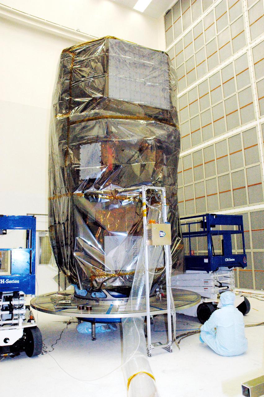 KENNEDY SPACE CENTER, FLA. - In Hangar AE at Cape Canaveral Air Force Station (CCAFS) in Florida, technicians with Spectrum Astro Inc. complete securing the plastic cover around the Swift spacecraft before moving it to the launch pad. The launch of the Swift observatory, a NASA spacecraft to pinpoint the location of gamma-ray bursts, is scheduled for Nov. 17 from Pad 17-A on CCAFS. Liftoff aboard a Boeing Delta II rocket is targeted at the opening of a one-hour launch window beginning at 12:09 p.m. EST. Gamma-ray bursts are distant, yet fleeting explosions that appear to signal the births of black holes. They are the most powerful explosions known in the universe, emitting more than 100 billion times the energy that the Sun emits in a year. Yet they last only from a few milliseconds to a few minutes, never to appear in the same spot again.