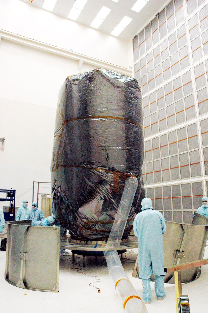 KENNEDY SPACE CENTER, FLA. - Boeing technicians in Hangar AE at Cape Canaveral Air Force Station (CCAFS) in Florida set up segments of the payload transfer canister that will be installed around the plastic-wrapped Swift spacecraft. The launch of the Swift observatory, a NASA spacecraft to pinpoint the location of gamma-ray bursts, is scheduled for Nov. 17 from Pad 17-A on CCAFS. Liftoff aboard a Boeing Delta II rocket is targeted at the opening of a one-hour launch window beginning at 12:09 p.m. EST. Gamma-ray bursts are distant, yet fleeting explosions that appear to signal the births of black holes. They are the most powerful explosions known in the universe, emitting more than 100 billion times the energy that the Sun emits in a year. Yet they last only from a few milliseconds to a few minutes, never to appear in the same spot again.