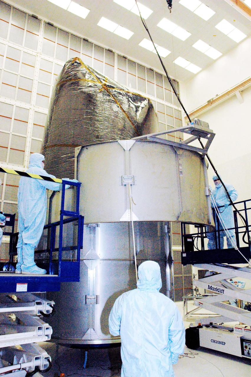 KENNEDY SPACE CENTER, FLA. - Boeing technicians in Hangar AE at Cape Canaveral Air Force Station (CCAFS) in Florida maneuver a segment of the payload transfer canister into place around the plastic-wrapped Swift spacecraft. The launch of the Swift observatory, a NASA spacecraft to pinpoint the location of gamma-ray bursts, is scheduled for Nov. 17 from Pad 17-A on CCAFS. Liftoff aboard a Boeing Delta II rocket is targeted at the opening of a one-hour launch window beginning at 12:09 p.m. EST. Gamma-ray bursts are distant, yet fleeting explosions that appear to signal the births of black holes. They are the most powerful explosions known in the universe, emitting more than 100 billion times the energy that the Sun emits in a year. Yet they last only from a few milliseconds to a few minutes, never to appear in the same spot again.