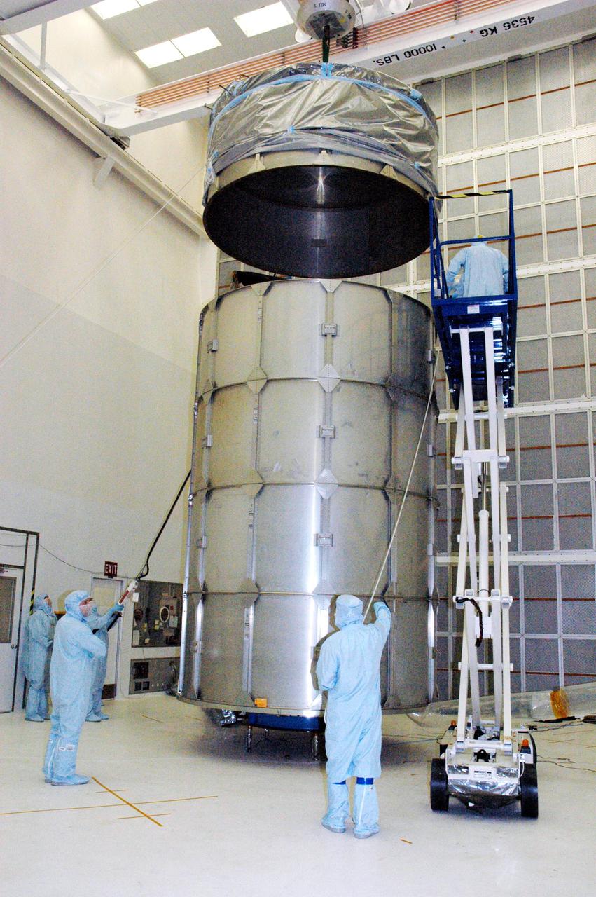 KENNEDY SPACE CENTER, FLA. - With four rows of payload transfer canister segments in place around the plastic-wrapped Swift spacecraft, Boeing technicians lower the top into place. The top holds an additional cover that will be lowered into place over the canister. The launch of the Swift observatory, a NASA spacecraft to pinpoint the location of gamma-ray bursts, is scheduled for Nov. 17 from Pad 17-A on CCAFS. Liftoff aboard a Boeing Delta II rocket is targeted at the opening of a one-hour launch window beginning at 12:09 p.m. EST. Gamma-ray bursts are distant, yet fleeting explosions that appear to signal the births of black holes. They are the most powerful explosions known in the universe, emitting more than 100 billion times the energy that the Sun emits in a year. Yet they last only from a few milliseconds to a few minutes, never to appear in the same spot again.