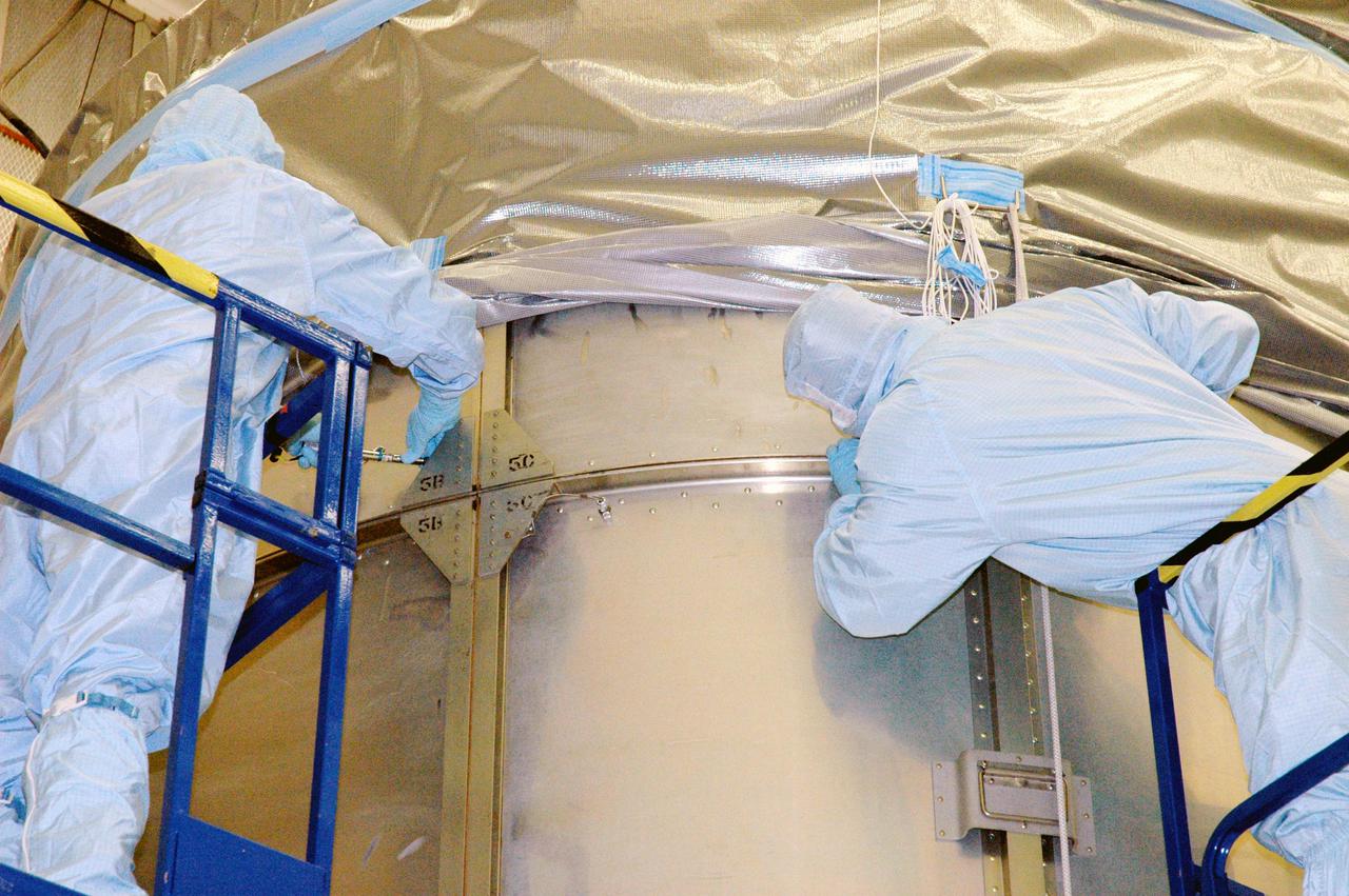 KENNEDY SPACE CENTER, FLA. - Boeing technicians in Hangar AE at Cape Canaveral Air Force Station (CCAFS) in Florida attach the top of the payload transfer canister to the lower segments that surround the plastic-wrapped Swift spacecraft. The top holds an additional cover that will be lowered into place over the canister. The launch of the Swift observatory, a NASA spacecraft to pinpoint the location of gamma-ray bursts, is scheduled for Nov. 17 from Pad 17-A on CCAFS. Liftoff aboard a Boeing Delta II rocket is targeted at the opening of a one-hour launch window beginning at 12:09 p.m. EST. Gamma-ray bursts are distant, yet fleeting explosions that appear to signal the births of black holes. They are the most powerful explosions known in the universe, emitting more than 100 billion times the energy that the Sun emits in a year. Yet they last only from a few milliseconds to a few minutes, never to appear in the same spot again.