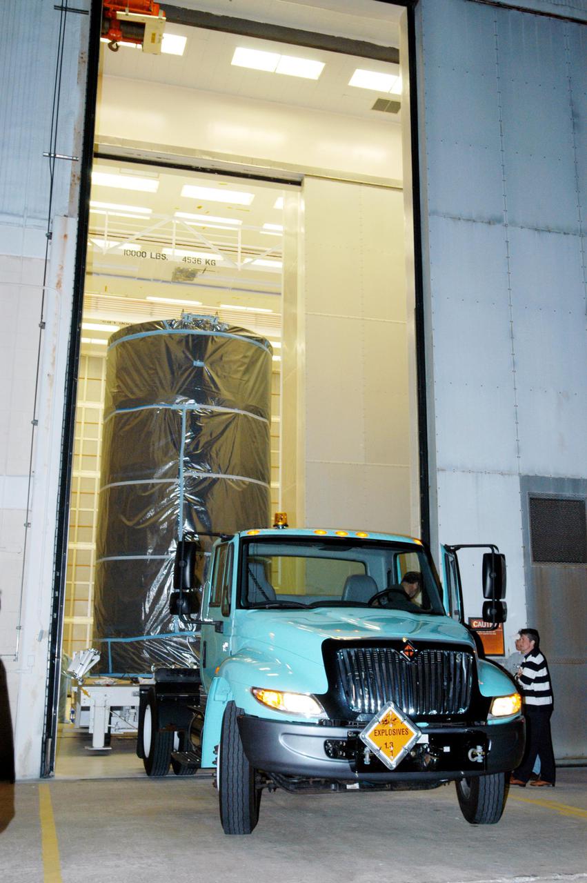 KENNEDY SPACE CENTER, FLA. - Wrapped inside a protective cover, the Swift spacecraft leaves Hangar AE at Cape Canaveral Air Force Station in Florida. It is being moved to Launch Pad 17-A and scheduled to launch Nov. 17. The liftoff aboard a Boeing Delta II rocket is targeted at the opening of a one-hour launch window beginning at 12:09 p.m. EST. A first-of-its-kind multi-wavelength observatory dedicated to the study of gamma-ray burst (GRB) science, Swift’s three instruments will work together to observe GRBs and afterglows in the gamma ray, X-ray, ultraviolet and optical wavebands. Gamma-ray bursts are distant, yet fleeting explosions that appear to signal the births of black holes.